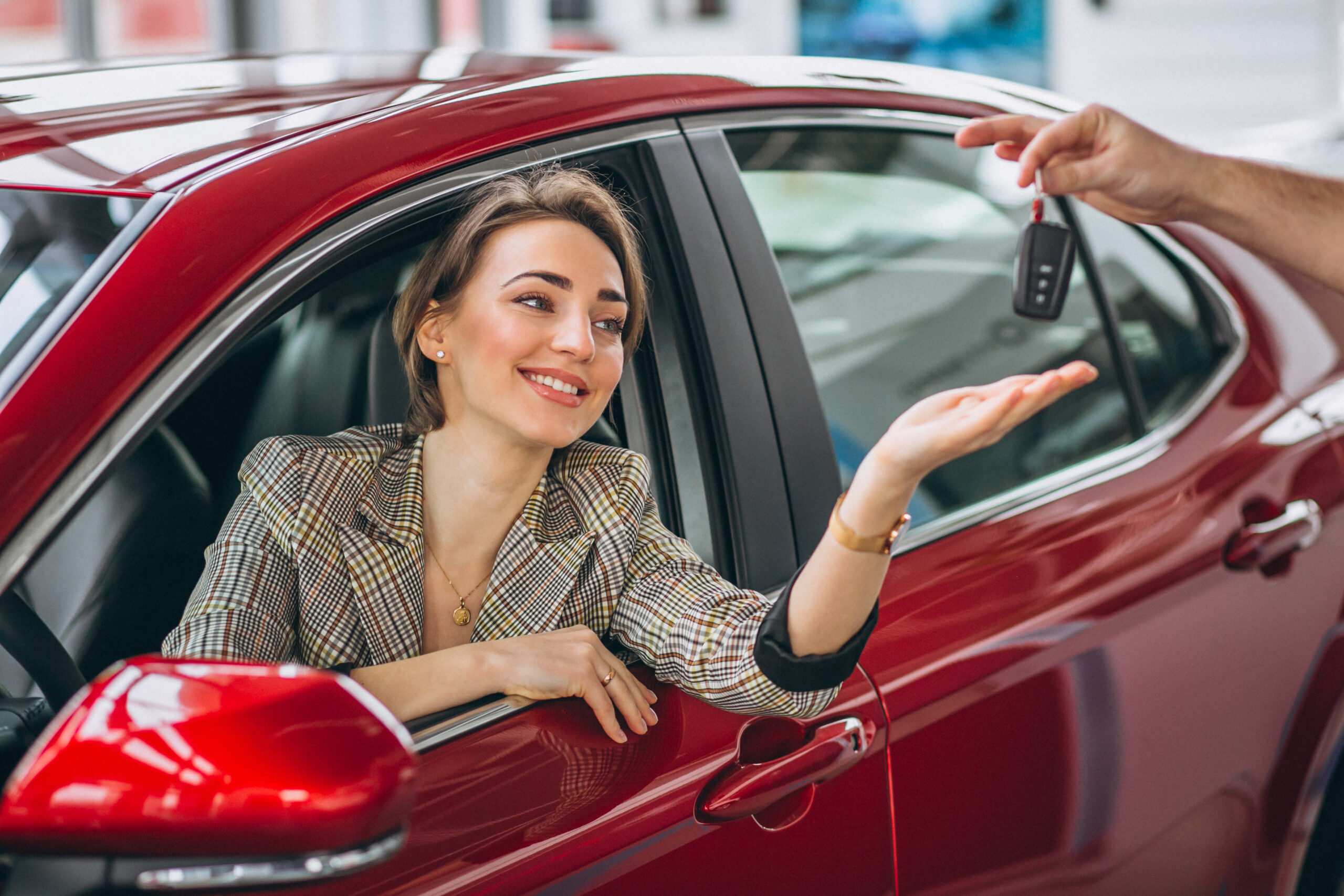 woman sitting in red car and receiving keys